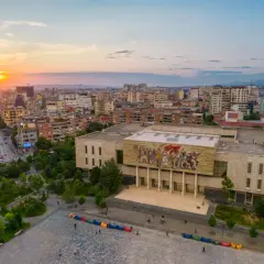 Zachód słońca nad Tirana, stolicą Albanii. Widok na plac z kolorowymi pufami i budynek z mozaiką.