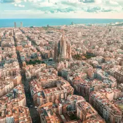 Widok z lotu ptaka na Eixample w Barcelonie, z Sagradą Familią górującą nad miastem i morzem w tle.