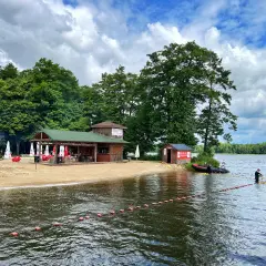 Plaża nad jeziorem w Szczecinku z barem i ratownikami przygotowującymi boje.