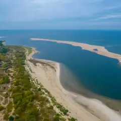 Piaszczysta mierzeja z zielenią i wodą, idealne miejsce, gdzie najcieplej nad morzem.
