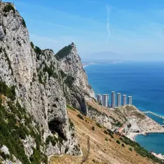 Majestatyczna skała Gibraltaru z widokiem na nowoczesne budynki i błękitne morze. Miasto Gibraltar rozciąga się u stóp klifu.