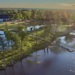 Malownicze mazury miejscowości nad jeziorem. Hotel z pomostami i spokojną wodą, otoczony zielenią i drzewami.