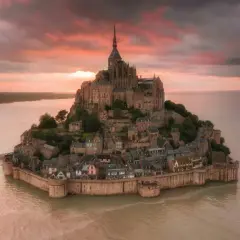 Bajkowy zamek na wodzie we Francji, Mont Saint-Michel, otoczony wodą o zachodzie słońca.