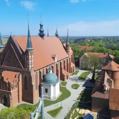 Widok z góry na Frombork zamek i katedrę. Czerwona cegła, zielone dachy i błękitne niebo tworzą malowniczy krajobraz.