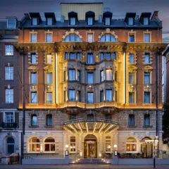 Elegancki hotel w Londynie z oświetloną fasadą i wejściem, nocą.