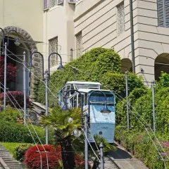 Bergamo kolejka wjeżdża po stromych torach wśród zieleni i zabytkowych budynków.