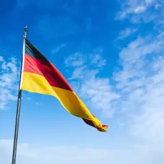 Flaga Niemiec na tle błękitnego nieba. Zastanawiasz się, ile kosztuje kawa w Niemczech?