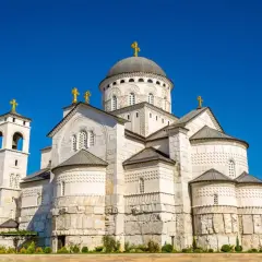 Majestatyczna cerkiew w Podgoricy, stolicy Czarnogóry, z dominującą kopułą i złotymi krzyżami.