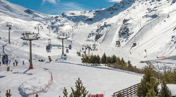 Widok na ośnieżone stoki narciarskie w Sierra Nevada z kolejkami linowymi i narciarzami.