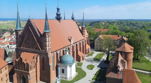 Widok z góry na Frombork zamek i katedrę. Czerwona cegła, zielone dachy i błękitne niebo tworzą malowniczy krajobraz.