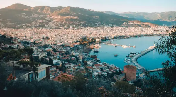 Widok na zatokę i miasto Alanya, z górami w tle. Widać port z łodziami i charakterystyczną czerwoną wieżę, część historycznego Alanya stare miasto.