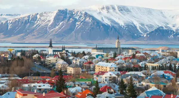 Kolorowe dachy Reykjaviku pod ośnieżonymi górami. Widok na miasto, kościoły i budynki, przypominający o jego położeniu na Islandii, gdzie lotniska są kluczowe dla podróży.