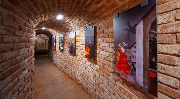 Galeria w ceglanym korytarzu prezentuje brneńskie nietypowe atrakcje: obrazy z legendarnymi stworzeniami i miejskimi pejzażami.