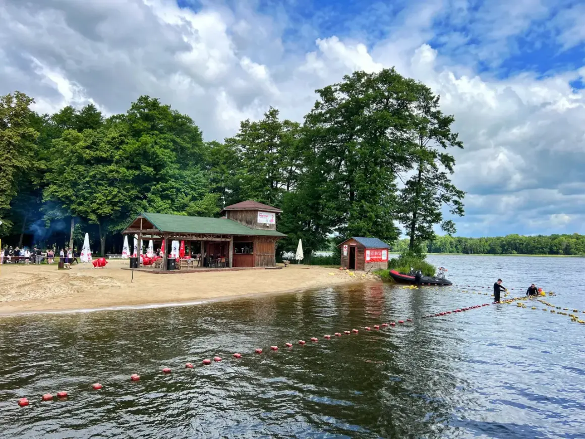 Plaża nad jeziorem w Szczecinku z barem i ratownikami przygotowującymi boje.
