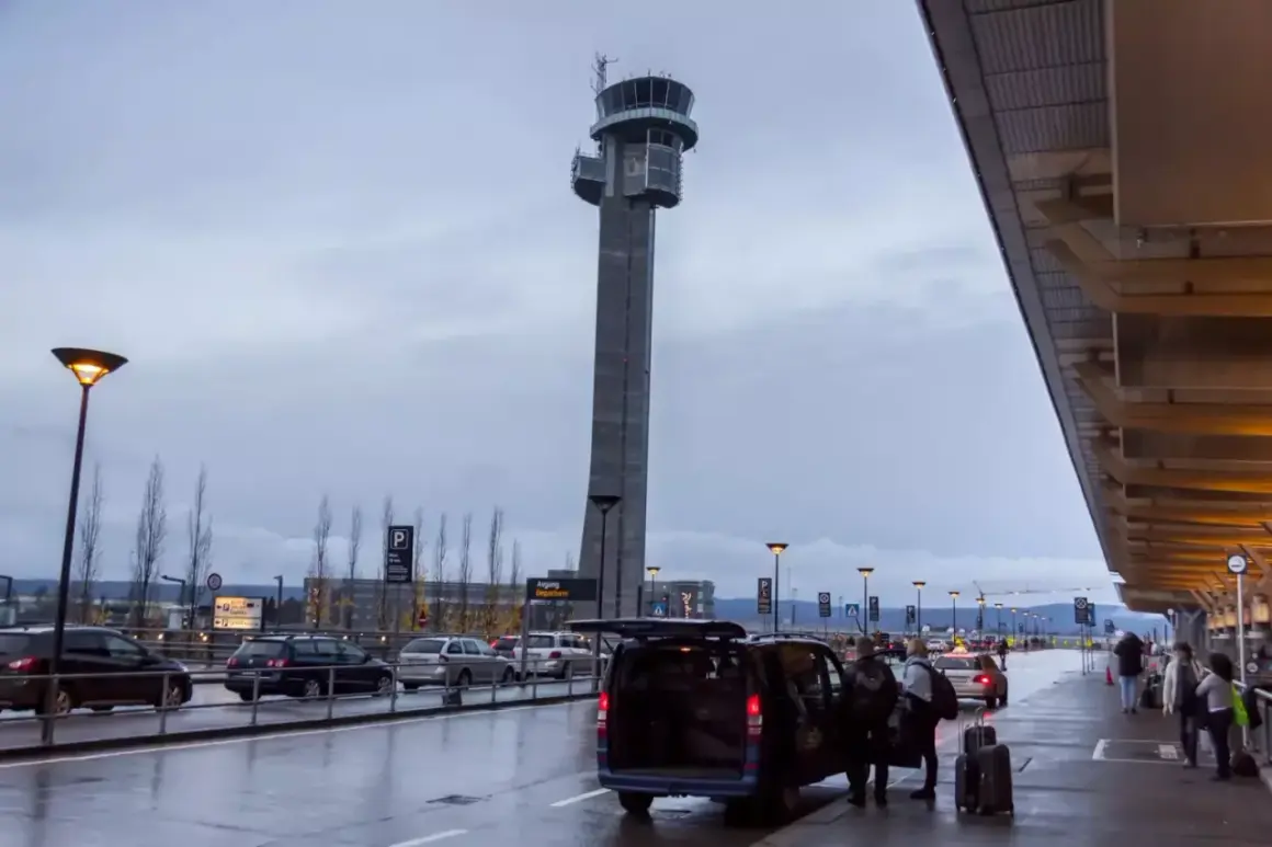 Wieża kontrolna na oslo lotnisko. Samochody czekają na pasażerów, a bagaże są wyładowywane.