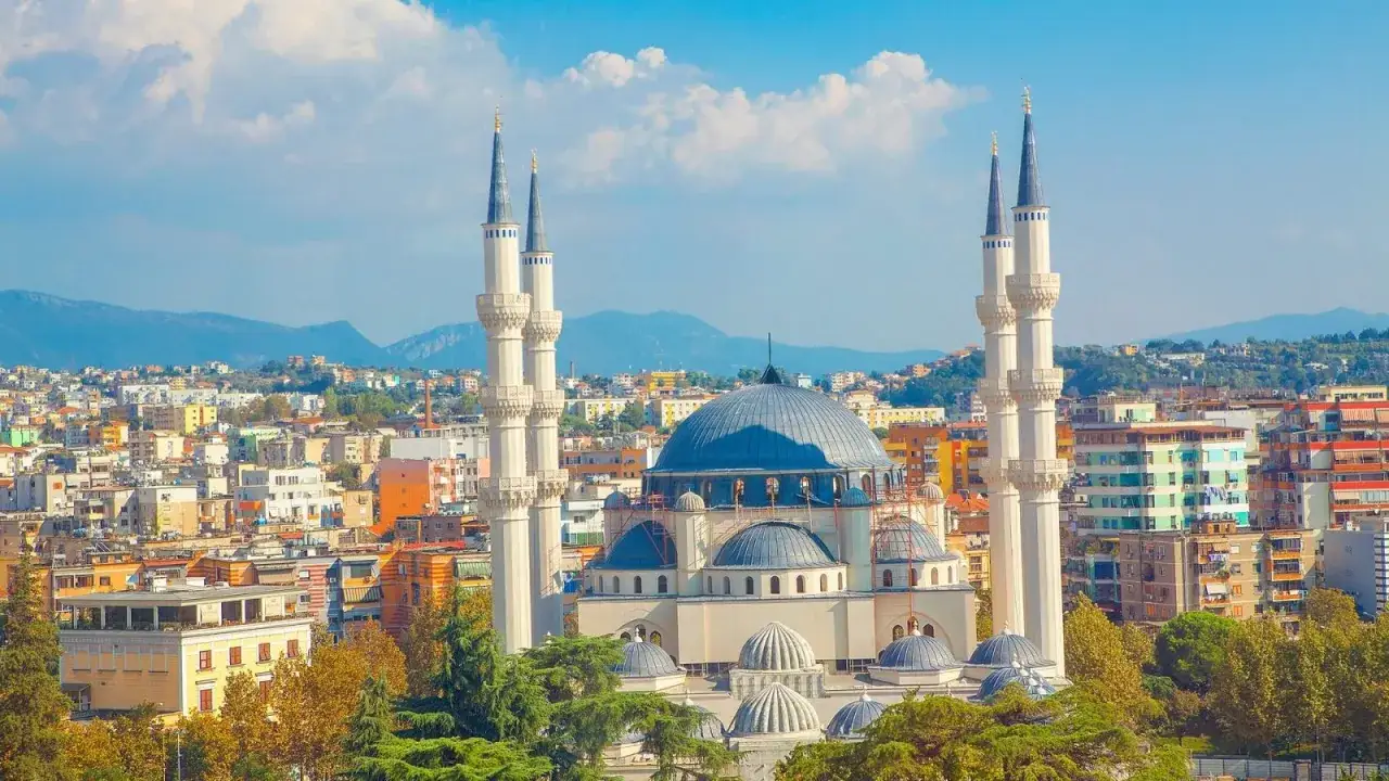 Imponująca panorama miasta, gdzie w centrum wznosi się wielka, błękitna kopuła meczetu. To serce Albania stolica, otoczone kolorowymi budynkami i zielenią.