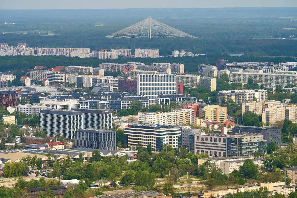 Widok na nowoczesne budynki Wrocławia z dalekim zarysem najwyższego budynku we Wrocławiu, Mostu Rędzińskiego.