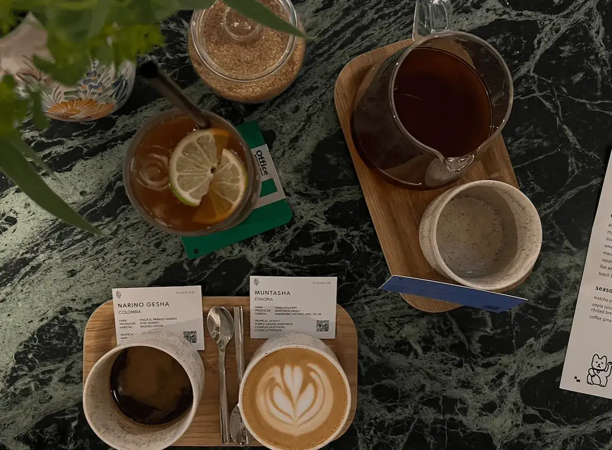 Dwie kawy, jedna z pianką, druga z plasterkiem limonki, na marmurowym blacie. Zastanawiasz się, ile kosztuje kawa w Czechach?