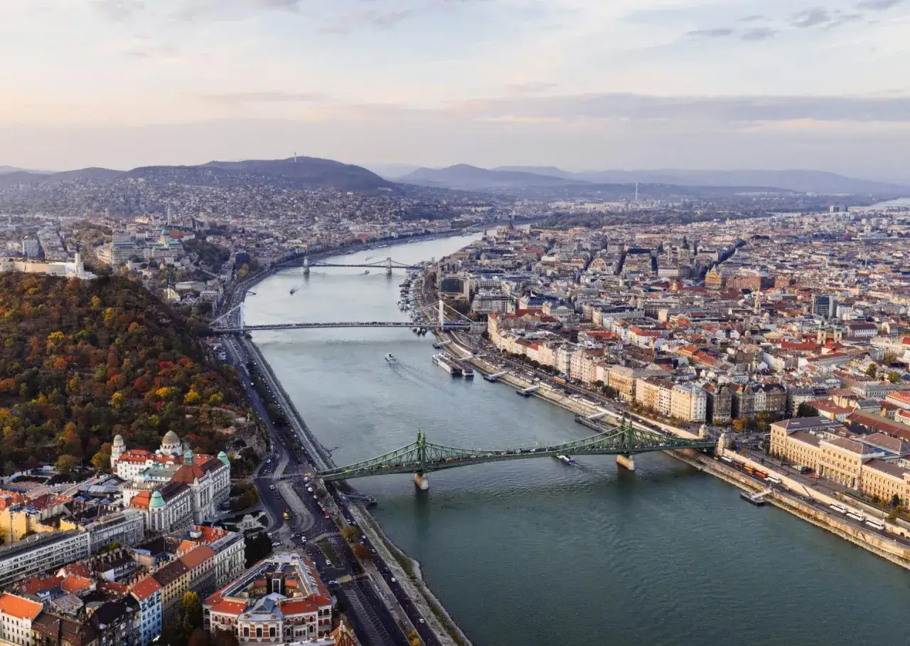 Widok na Budapeszt z lotu ptaka, z rzeką Dunaj przecinającą miasto i zielonym mostem w centrum.