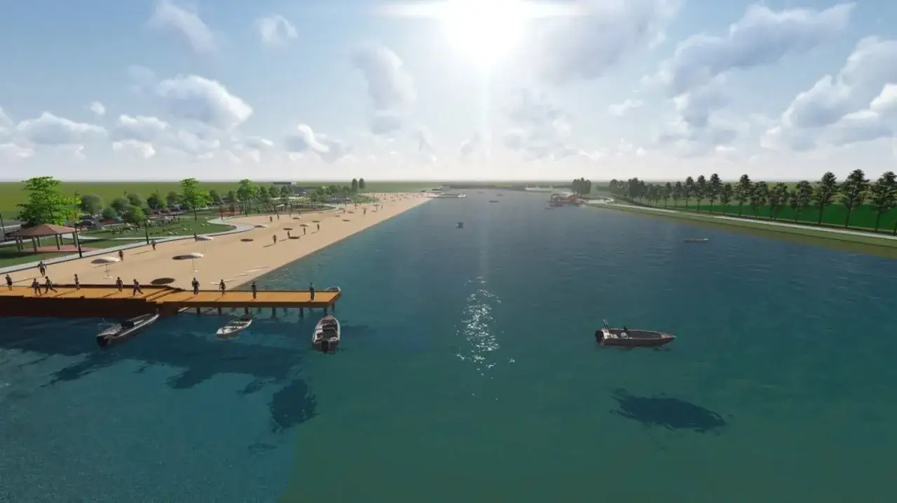 Słoneczny dzień nad zalewem żyrardowskim. Ludzie spacerują po plaży, cumują łodzie przy pomoście.