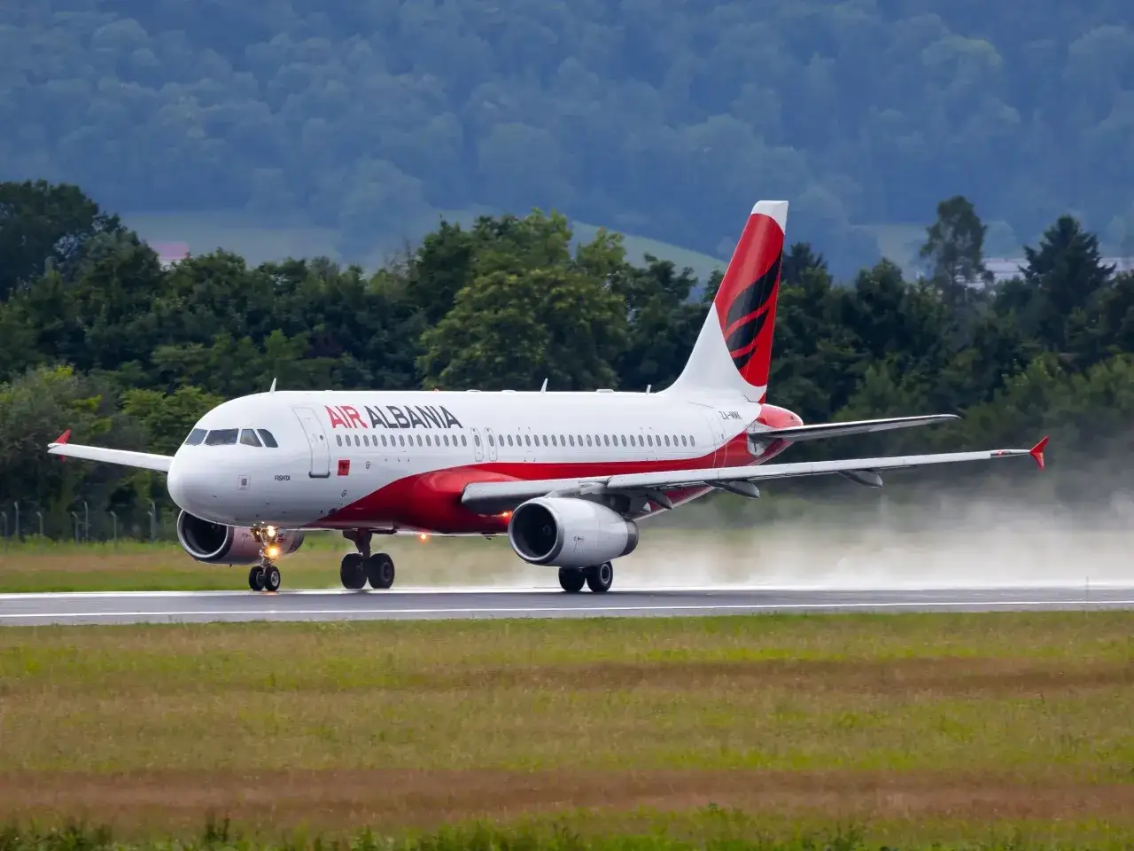 Samolot Air Albania na pasie startowym. W tle zielone wzgórza i lasy. Lotniska w Albanii czekają na pasażerów.