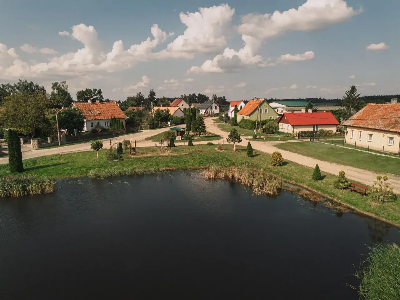 Malownicza wieś nad jeziorem, z kolorowymi domami i zielenią, to obraz najpiękniejszych wsi na Mazurach.