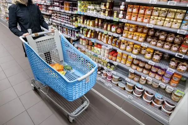 Kosz z zakupami w holenderskim supermarkecie. Na półkach dżemy, miody i masła orzechowe. Sprawdzam ceny w Holandii.