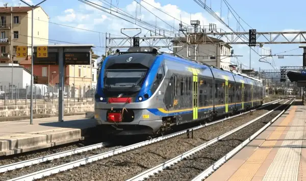Nowoczesny pociąg wjeżdża na stację, przypominając miejski transport, jak neapol metro.