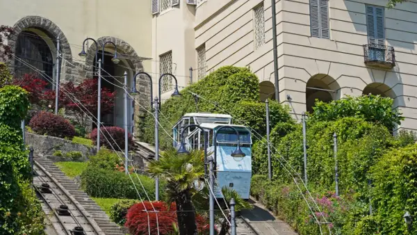 Bergamo kolejka wjeżdża po stromych torach wśród zieleni i zabytkowych budynków.